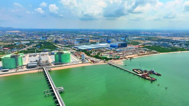 An LNG plant appear as a complex of large industrial buildings, storage tanks, pipelines. The plant would likely be situated in a large, open area with significant security measures in place. Drone
