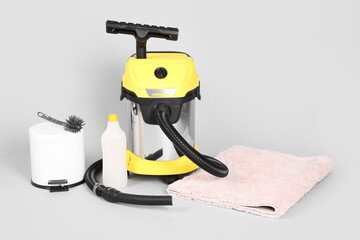 Naklejka premium Vacuum cleaner with supplies and carpet on grey background