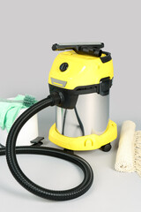 Vacuum cleaner with supplies and carpet on grey background