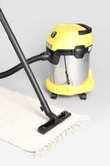 Vacuum cleaner with rug on grey background