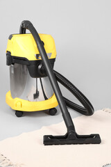 Vacuum cleaner with rug on grey background