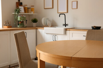 Interior of stylish kitchen with white counters, dining table and chairs