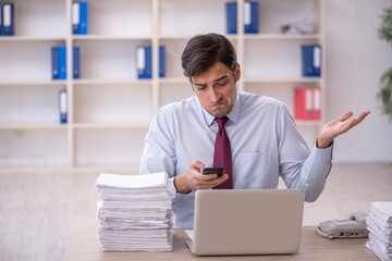 Fototapeta premium Young male employee and too much work in the office