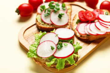Board with delicious radish bruschettas on beige background