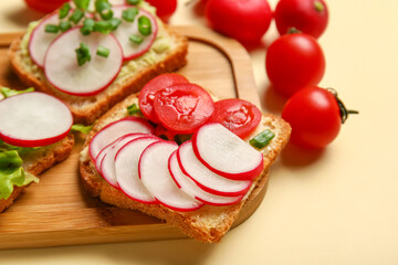 Board with delicious radish bruschettas on beige background