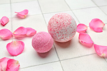 Bath bombs with floral petals on white tile background, closeup