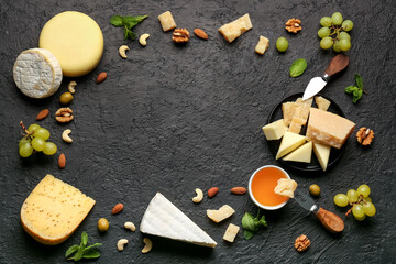 Frame made of tasty cheese, nuts, grapes and honey on black background