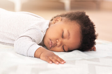 Adorable, bed and baby sleeping in home on blanket for rest, nap time and dreaming in nursery. Childcare, newborn and cute, tired and African child in bedroom sleep for comfort, relaxing and calm