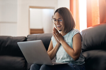 Home, excited and woman with a laptop, couch and happiness with website launch, connection and joy. Female person, girl or freelancer on a sofa, pc or technology with announcement, internet and email