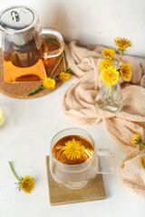 Fototapeta na wymiar Glass cup of healthy dandelion tea and teapot on white table