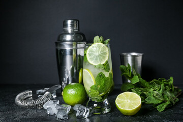 Glass of cold mojito and ingredients on dark background