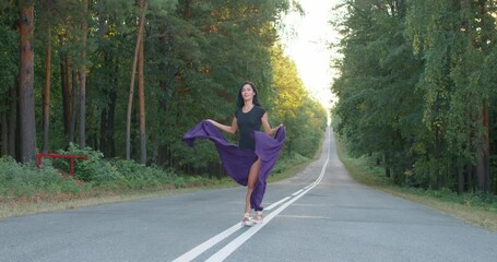 sportswoman raising her legs up. ballerina in a jump double exposure nature concept Slow motion. Gymnast girl doing exercise with purple fabric, cloth in nature