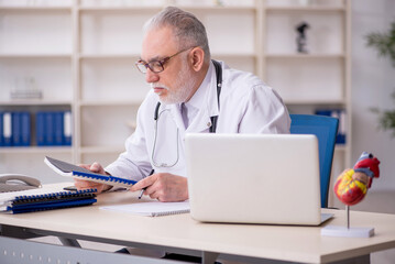 Old male doctor cardiologist working in the clinic