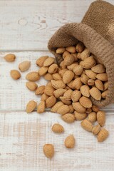 Scattered bitter almonds on a white background, nuts in shell, unshelled, in a bag, nutritious food, protein, trace elements, stocks for the winter, storage, background, photo, text, background image