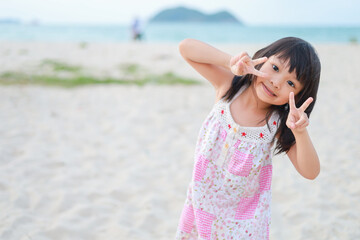 Portrait​ image​ of​ baby 5-6 years​ old​. Happy Asian child girl playing sand on the beach at the sea. In the summer season.