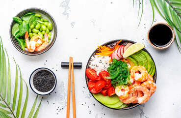 Poke bowl with shrimp, avocado, radish, carrot, tomato, seaweed and white rice. White table...