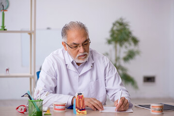 Old male dentist working in the clinic