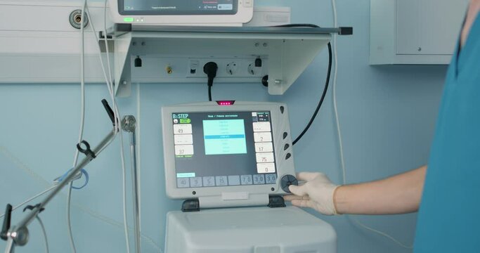 Modern equipment in surgery room hels to save lives, life, showing multiple signs of human body condition. Doctor controlling the work of equipment. Artificial lung ventilation apparatus in modern
