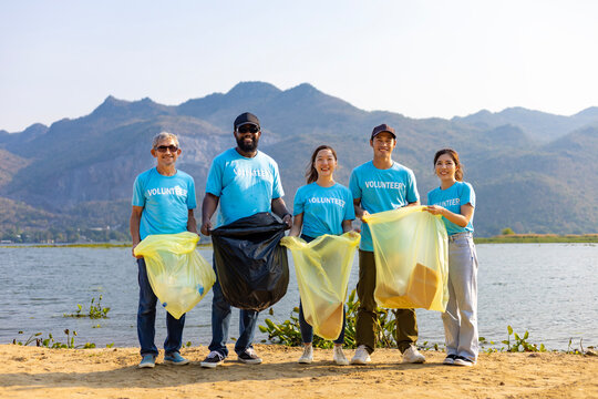 Team of young and diversity volunteer worker group enjoy charitable social work outdoor in cleaning up garbage and waste separation project at river beach