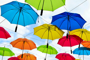 colorful parasol sun protection. bright umbrellas suspended overhead on metal wires. climate change and global warming concept. summer travel tourism and vacation theme. design and urban environment.