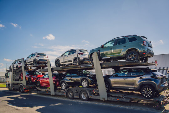 Car carrier trailer transports cars on highway at blue sky background.