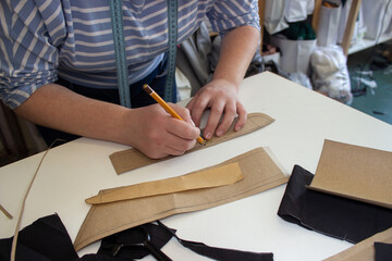 Professional seamstress creates a pattern for clothes in the workshop. The process of sewing clothes. Fashion designer creates a new model of clothes.