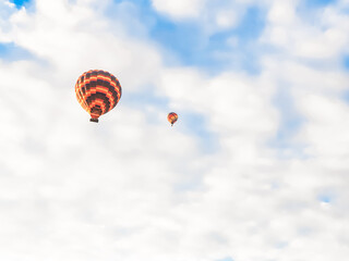 Flying in sky many bright colored beautiful balloons into air in Cappadocia in mountains early at sunrise, dawn. Filling balloon with hot air from burner, big basket. Tourists excursion, cloud flight
