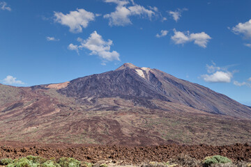 The famous El Teide volcano in Tenerife, Canary islands, Spain. Volcanic landscape in front a blue sky and white clouds.
