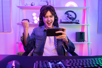 Male  Gamer with Headset Raised His Fist After Win the Online Video Game Match on his Smartphone