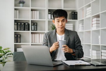 Asian business man executive manager looking at laptop watching online webinar training or having virtual meeting video conference doing market research working in modern office.