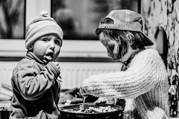 Black and white photo of happy brother and sister eating a meal.