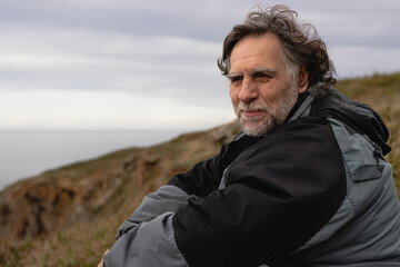 Happy mature man with beard sitting on the mountain