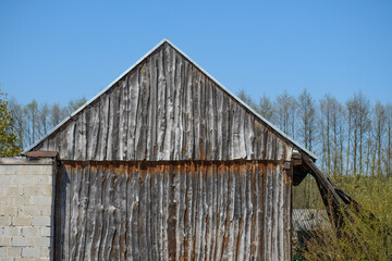 Stara drewniana stodoła w ciepły bezchmurny dzień z błękitnym niebem w tle  - obrazy, fototapety, plakaty