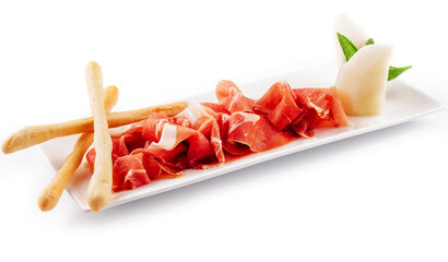 Jamon Serrano, Prosciutto Crudo or Parma ham and breadsticks on white plate
