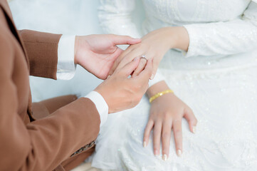 Obraz na płótnie Canvas Groom wear wedding rings to left finger of bride, Muslim wedding, Wedding Poster, Close up hand.