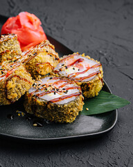 Served warm sushi with ginger and wasabi on a black stone plate