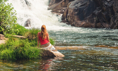 Woman sitting enjoying amazing waterfall- Galicia, Spain