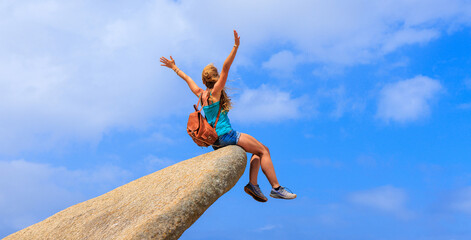 Woman sitting on mountain peak on blue sky- achievement, travel, adventure, freedom concept (...