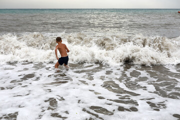 Kid on shore of stormy Black Sea