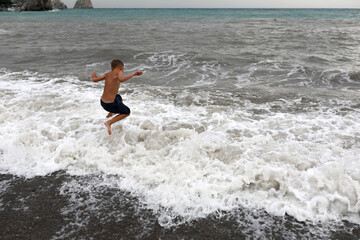 Kid playing on shore of stormy Black Sea