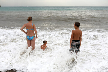 Mother with two sons on shore of stormy Black Sea