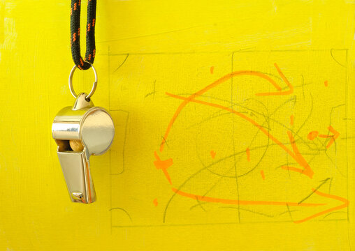 Whistle of soccer referee or coach and soccer tactics scribble on yellow background,close up.