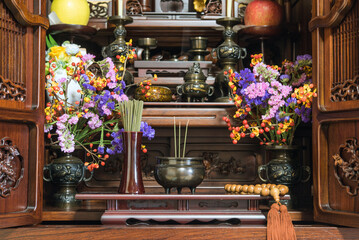 Fototapeta na wymiar 日本のお仏壇　仏花と数珠と線香の煙　Incense burner on Butsudan (household Buddhist altar) in Japanese house