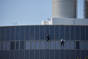 高層ビルの外壁を掃除する高所作業員の姿