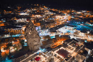 Fototapeta premium Aerial view of illuminated streets, fairy chimneys and cave hotels at Goreme village, Nevsehir province, Cappadocia, Turkiye