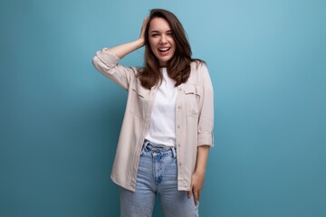 pretty 25 year old woman in a casual look smiles cutely on a blue background
