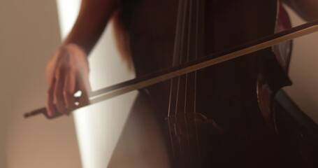 Single woman playing the cello, close-up and medium close-up, cello bow and strings, smooth transitions of the camera from focus to out-of-focus, beautiful filmic, artistic shots.