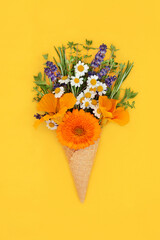 Summer edible flowers and fresh herbs in ice cream waffle cone  Minimal surreal nature food concept on vibrant yellow background. Flay lay copy space.
