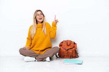 Uruguayan student woman sitting one the floor isolated on white background pointing up and surprised