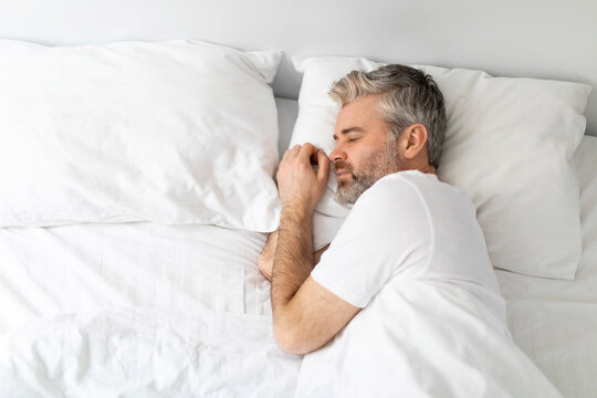 Top view of middle aged man sleeping alone in bed